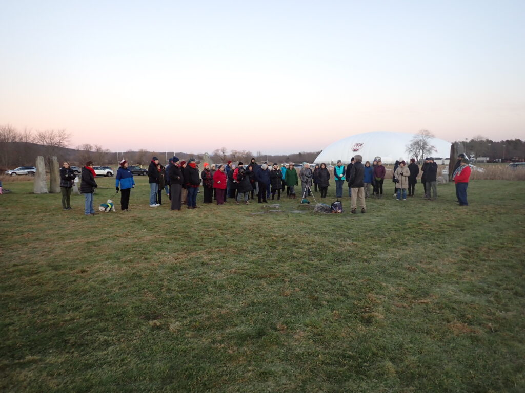 a crowd of people attending a presentation about the winter solstice at the UMass sunwheel