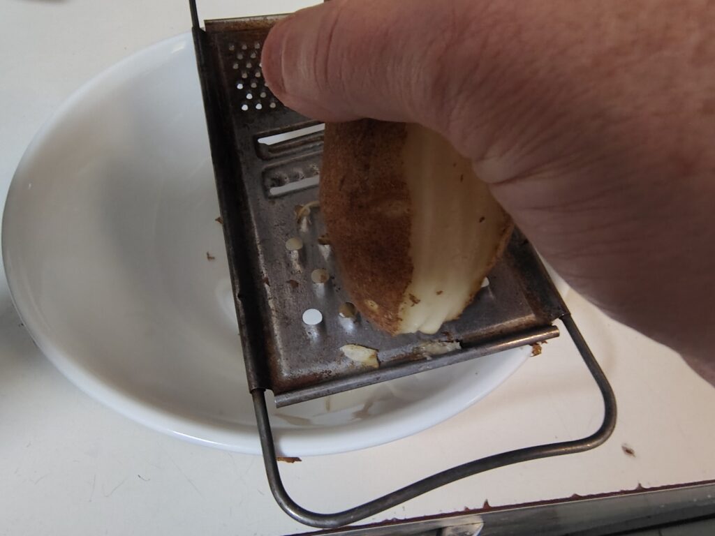 Grating a hemispherical band around the potato.
